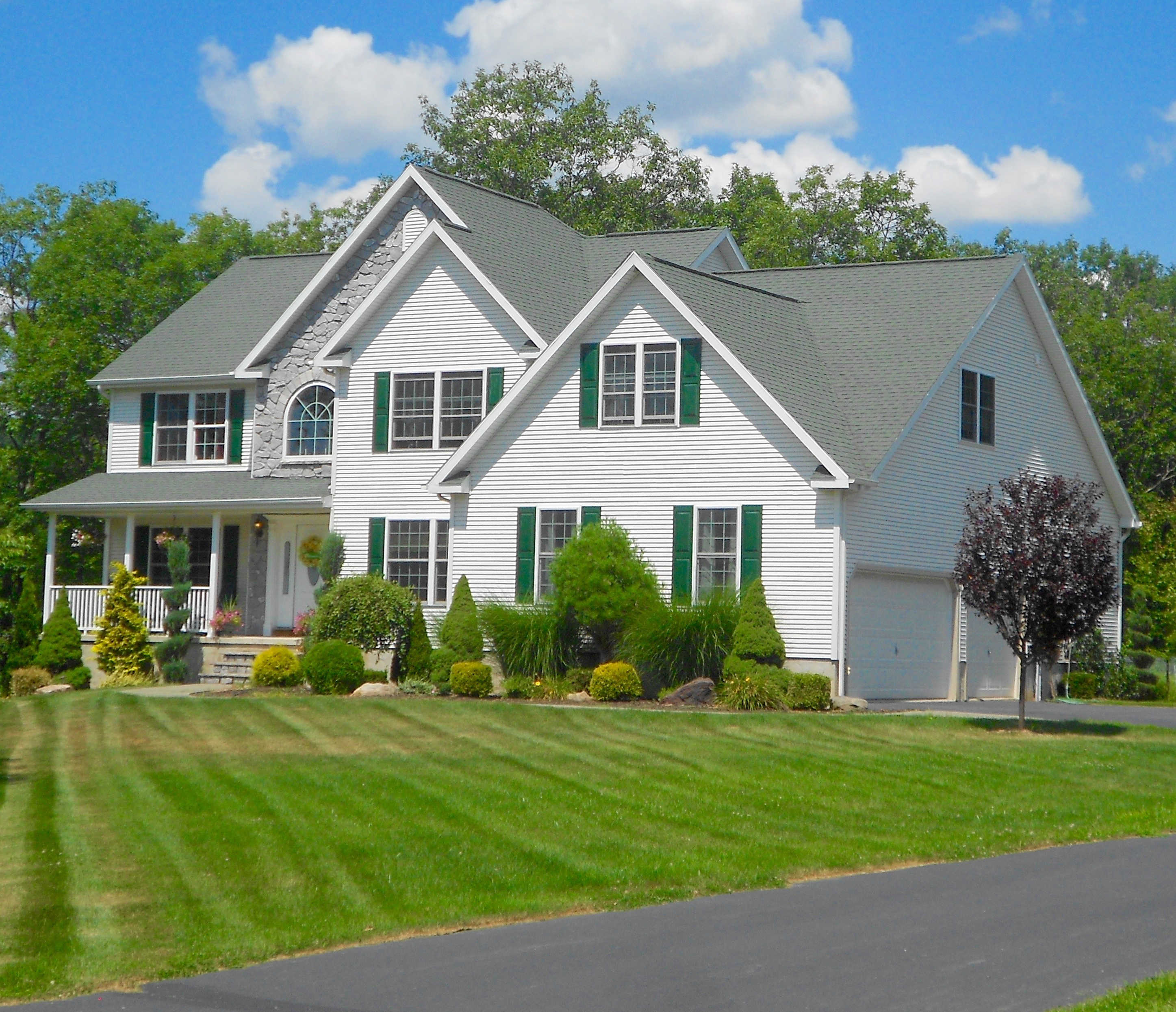 A well-kept suburban home with green shutters and a manicured lawn